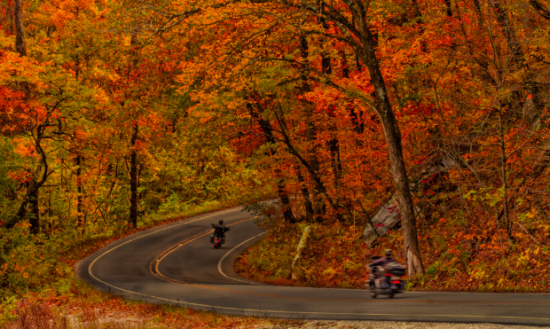 Two motorcycles on a winding Ozark mountain road during the fall